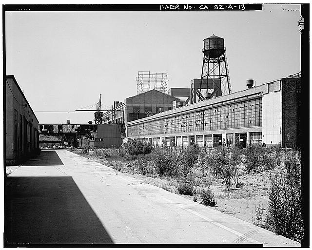 Ford Long Beach Assembly Plant OVERALL SOUTH ELEVATION FROM STORAGE SHED D, SHOWING SHOP A, CRANE, SIGN STRUCTURE, AND WATER TOWER. NOTE TOWERS OF BRIDGE BEHIND PLANT. 